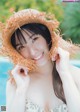 A woman in a straw hat posing by a pool.