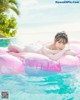 A woman in a bikini laying on an inflatable raft in a pool.