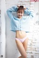 A woman in a blue sweater and pink panties posing for a picture.