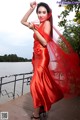 A woman in a red dress standing by the water.