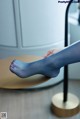 A woman's feet in blue tights sitting on a table.
