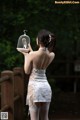 A woman in a white dress holding a bird cage.