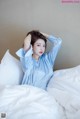 A woman in a blue shirt is laying on a bed.