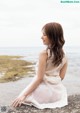 A woman sitting on a rock by the ocean.