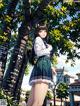 A girl in a school uniform standing next to a tree.