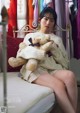 A woman sitting on a bed holding a teddy bear.