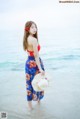 A woman standing in the ocean holding a straw hat.