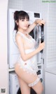 A woman in a white lingerie standing next to a washing machine.