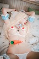 A woman laying on a bed with a carrot in her mouth.