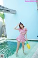 A woman in a pink dress standing in a pool.