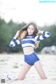 A woman in a blue and white striped top and shorts on the beach.