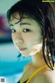 A woman in a yellow bikini standing in a pool.